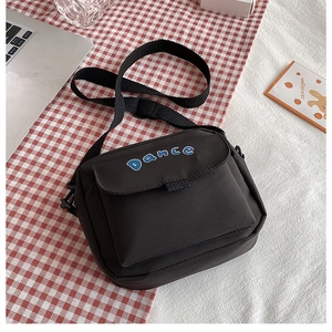 Close-up of black nylon crossbody bag with white Dance logo and adjustable strap
