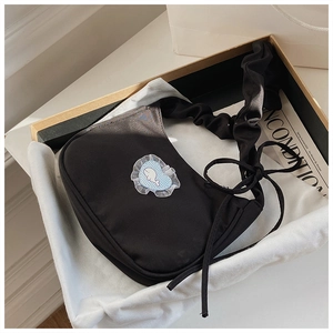 Detail einer schwarzen Falten-Umhängetasche mit Wal-Aufnäher und Schleife in einer Geschenkbox