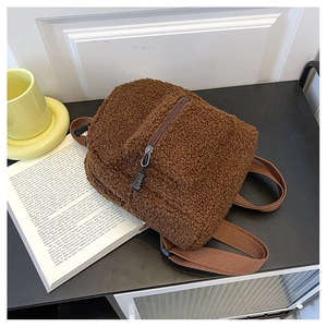 Detailed view of brown faux lamb wool mini backpack on a table with a book and coffee cup
