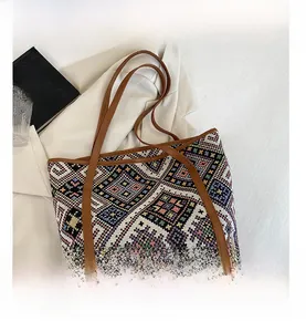 Close-up of ethnic geometric weave pattern and brown leather handles on the tote bag
