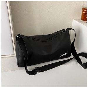 Détail d'un sac bandoulière en nylon noir avec étiquette fashion sur un comptoir blanc