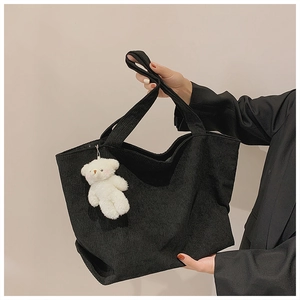 Close-up of black corduroy tote bag featuring a cute white plush bear pendant detail