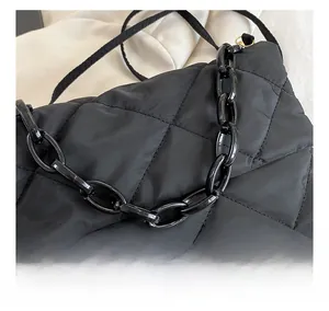 Close-up of black quilted nylon bag featuring detailed stitching and a chunky chain strap