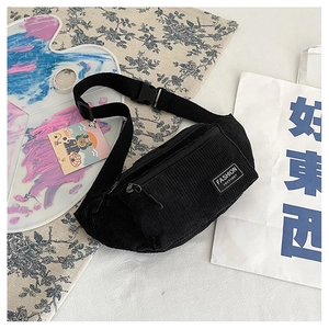 Detail of black corduroy chest bag featuring a white Fashion Instinct label and nylon strap