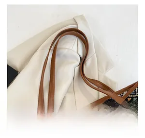 Detail view of brown leather straps on a colorful ethnic woven jacquard tote bag