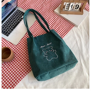Dettaglio della borsa tote in velluto a coste verde scuro con ricamo di orsetto