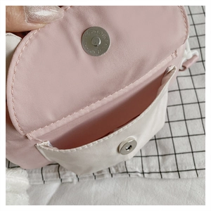 Detail of pink and white crossbody bag with magnetic buckle closure and front pocket