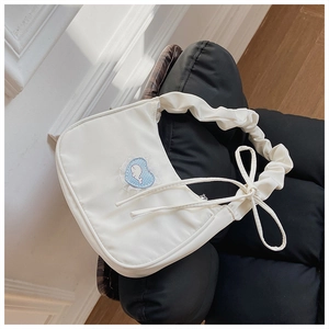 Detail der weißen gefalteten Schultertasche mit blauem Herz-Wal-Spitzenaufnäher