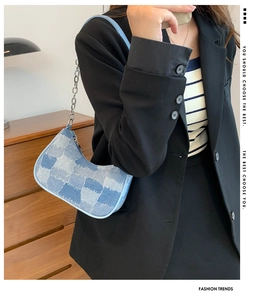 Chic blue patchwork denim shoulder bag with silver chain strap worn by a model