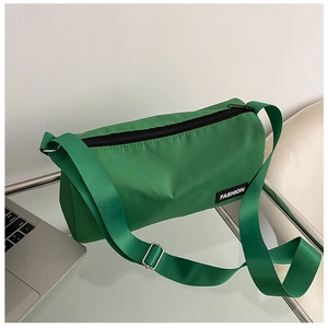 Détail du sac bandoulière en nylon vert avec étiquette mode noire et fermeture éclair