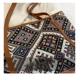 Close-up of geometric jacquard fabric and brown leather strap on ethnic tote bag