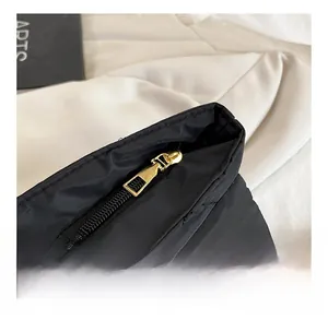 Detailed close-up of golden metal zipper and black quilted padded texture on luxury handbag