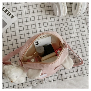 Detail of pink canvas crossbody bag with rabbit ears, showing interior storage capacity