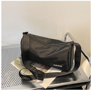 Détail du sac bandoulière baril en nylon noir avec étiquette fashion sur un chariot