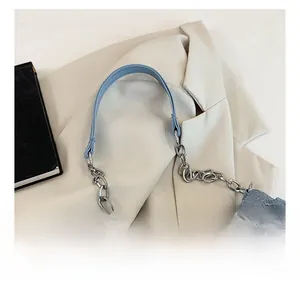 Detail of blue denim shoulder bag with silver chain strap and star pattern texture