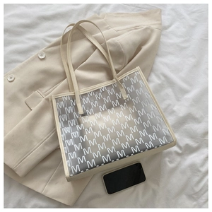Top view of a minimalist cream PU tote bag with monogram texture and matching handles