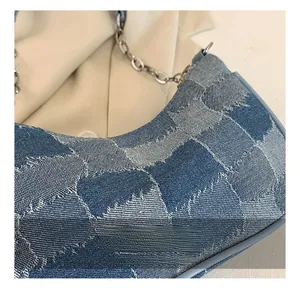 Detail of blue denim patchwork shoulder bag with elegant silver metal chain strap
