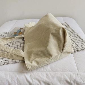 Minimalist beige corduroy tote bag with wide straps on white bedding for casual daily use