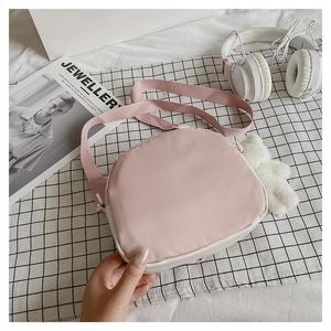 Flat lay of pink and beige crossbody bag with cute plush bear charm on plaid cloth
