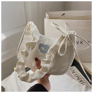 Detail einer weißen Plissee-Handtasche mit hellblauem Karo-Herz und Wal-Aufnäher