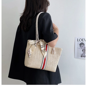 Detail of straw tote bag with red stripes and silk scarf on a white rope handle