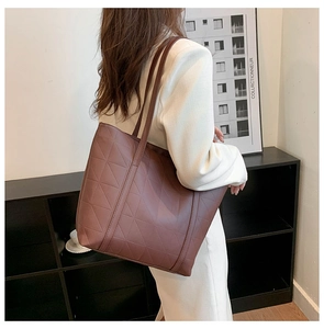 Detail of a deep coffee quilted tote bag with triangle stitching and leather texture