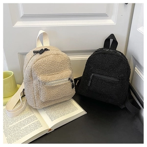 Close-up of fluffy faux shearling mini backpacks in black and beige with front zipper