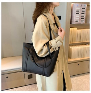 Detail of black quilted tote bag with geometric stitching texture on faux leather