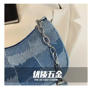 Detailed macro view of blue denim texture and silver chain strap on star pattern bag