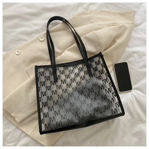 Detail of transparent PVC tote bag with M letter pattern and black leather handles