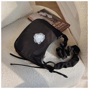 Detailansicht der schwarzen Schultertasche mit blauem Karo-Herz und gerafftem Träger