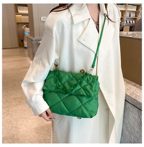 Macro view of green quilted chain bag with detailed diamond stitching and glossy finish