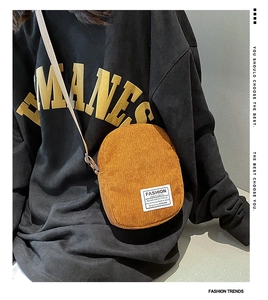 Detail of tan corduroy square crossbody bag with white fabric label and zipper texture