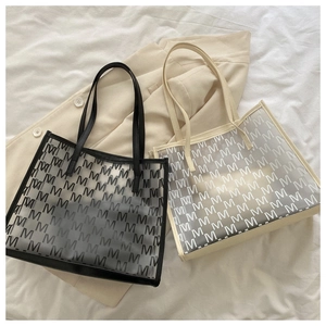 Detail of trendy PU tote bags in black and cream featuring stylish all-over M pattern