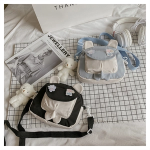 Detail of cute cartoon bear ear crossbody bags in blue and white canvas with bear charms