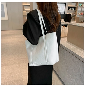 White quilted tote bag with diamond pattern shown on model in minimalist cafe setting