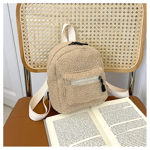 Detail of mini fleece backpack in beige showing fuzzy texture and white strap on a chair