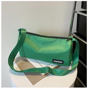 Détail du sac bandoulière en nylon vert avec sangle réglable et étiquette mode sur podium blanc