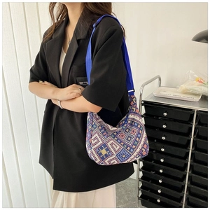 Détail du sac hobo en tricot jacquard avec motifs géométriques et bandoulière bleue