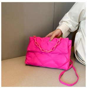 Close-up of pink quilted crossbody bag with stylish large plastic chain and fine strap