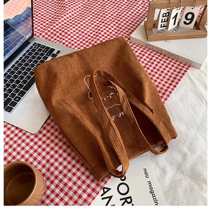 Borsa tote in velluto a coste marrone con ricamo a gatto su una scrivania