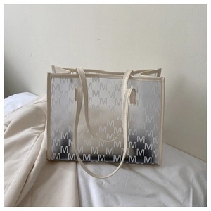 Detail of a large translucent tote bag with white M-pattern print on a white bed background
