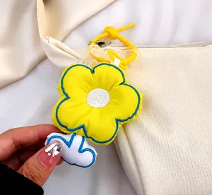 Détail du pendentif fleur en peluche jaune avec breloque nuage blanc sur sac en toile