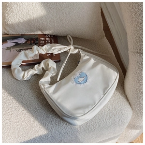 Detail der cremefarbenen Halbmondtasche mit Blauwal-Herz-Patch und gerafftem Trageriemen