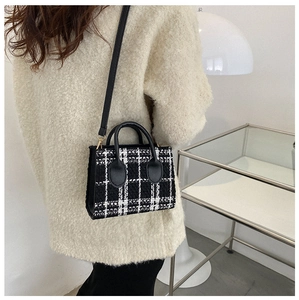 Détail du sac bandoulière en tweed noir et blanc avec anses en cuir et longue bandoulière