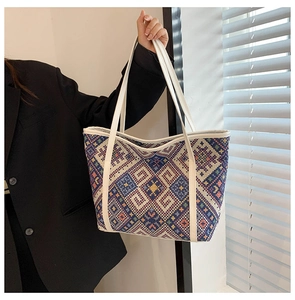Détail d'un grand sac cabas tissé aux motifs ethniques et aux poignées en cuir blanc