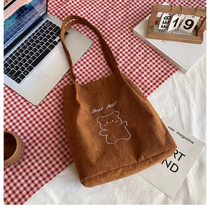 Vista dettagliata della borsa in velluto marrone con ricamo orso e scritta Bear Bear