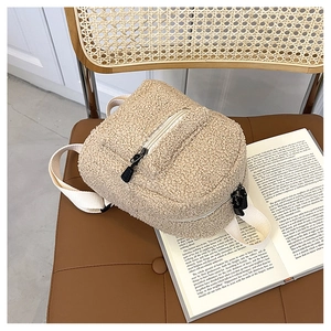 Close-up of a beige faux shearling mini backpack with fluffy texture on leather background