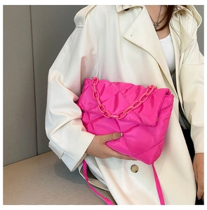 Detail of pink quilted chain bag on beige coat featuring glossy fabric and acrylic strap
