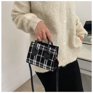 Details der klassischen schwarz-weißen Tweed-Umhängetasche mit Ledergriffen und Metallringen